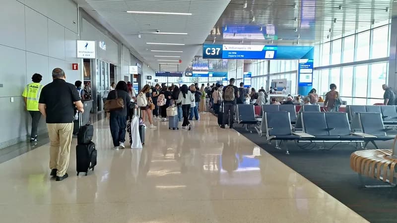 Passengers crowd a concourse at Hartsfield-Jackson Atlanta International Airport beneath departure boards.