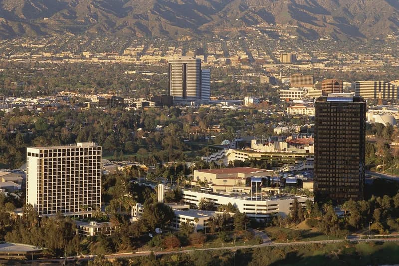 Aerial view of investigators examining the burned wreckage of a news helicopter in a lot between commercial buildings in Chatsworth, Los Angeles.